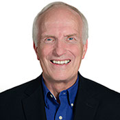 A headshot photo of Dave Jewitt wearing a dark sportsjacket and a dark blue button up shirt.