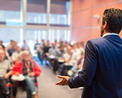A Your One Degree coach, wearing a blue sportsjacket, discusses the program to a room full of people.